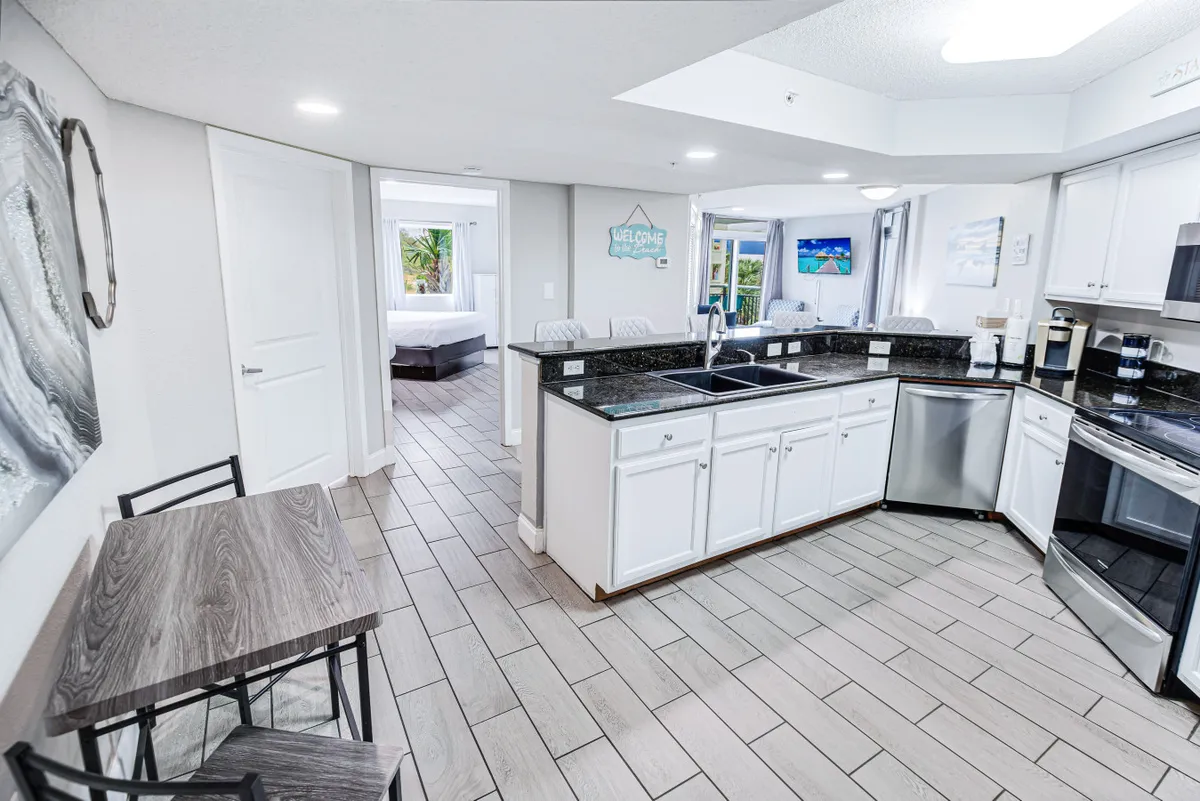 A stylish, inviting dining and kitchen area with a modern kitchen island, stainless steel appliances, and a dining table set for meals. The open layout encourages easy flow for socializing and dining.