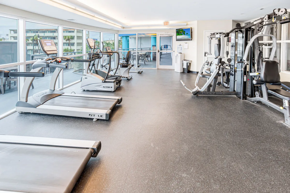 This energetic interior image displays a modern fitness center equipped with treadmills, weight machines, and large windows that let in ample light. The space is lively, inviting, and designed for both group workouts and solo training sessions.